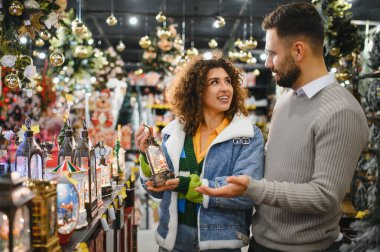 Mutlu çift bir mağazadan şenlikli süsler ve fenerler seçiyor, yaklaşan tatil sezonunun tadını çıkarıyor.