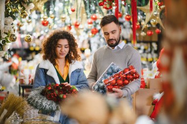 Bayram süslerini ve çelenkleri seçen genç çift, kış kutlamalarına hazırlanıyor.