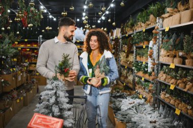 Mutlu çift bir mağazadan küçük köknar ağaçları ve diğer tatil süslemeleri seçerek festival sezonuna hazırlanıyor.