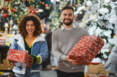 Mutlu çift gülümsüyor ve bayram alışverişi yaparken hediye kutularını tutuyorlar.