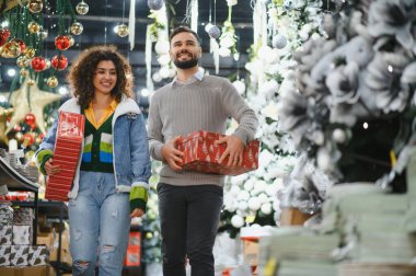 Genç çift bayram kutlamaları için hediye paketleriyle bir bayram mağazasında dolaşıyorlar.