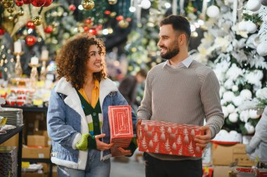 Mutlu çift gülümsüyor ve iletişim kuruyor, Noel hediyelerini tutuyorlar bayram için hediye seçiyorlar.