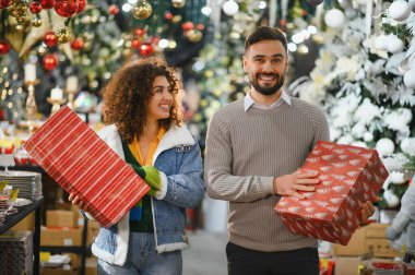 Mutlu çift, kış tatili boyunca bir bayram mağazasında paketlenmiş hediye kutularını seçip taşıyor.