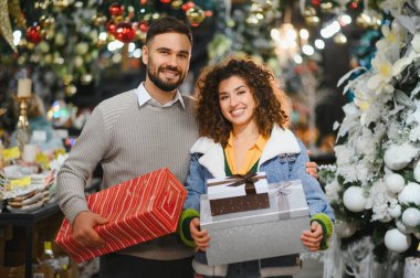Noel alışverişi sırasında hediye kutularıyla poz veren mutlu genç çift, Noel 'i ya da yeni yılı kutluyorlar.