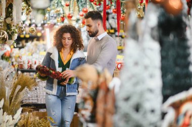 Bayram çelengi seçen çift, bayram tatili ve geleneklerini kutlamak için bir şeyler alıyor.
