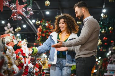 Mutlu çift Noel Baba heykelciklerini ve bayram sezonuna hazırlanmak için perakende mağazasından şenlik süslerini seçiyor.