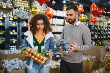 Bir çift Noel ağacı süsü seçiyor, bayram sezonu alışverişi sırasında perakende mağazasında karar veriyor.