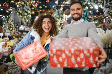 Mutlu çift gülümsüyor ve bayram hediyelerini sunuyor, bayram sezonunu kutluyor ve hediye alışverişinin tadını çıkarıyor.