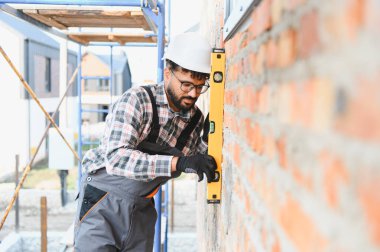 İnşaat işçisi, yeni inşa edilmiş tuğla duvar seviyesini kontrol ediyor.