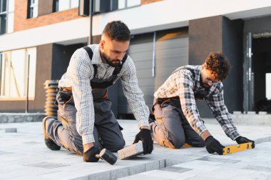 Profesyonel inşaatçılar yeni bir inşaat sahasına tuğla döşeyerek, katı ve dayanıklı bir yüzey sağlıyorlar.