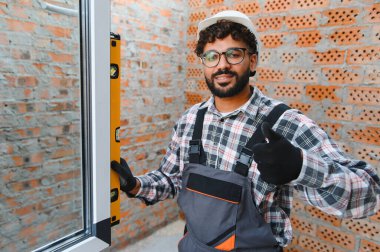 İnşaat alanına yeni bir araç kullanarak yeni pencere kuran mutlu inşaatçı. Kaliteli ev geliştirme işi