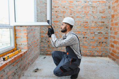 Konut yenileme ve enerji verimliliği güncellemesi sırasında modern pvc pencere çerçevesine uyan sabit şapka ve üniforma yükleyici