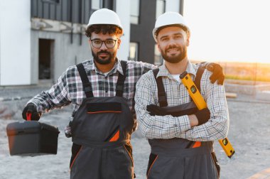 Yeni bir inşaat sahasında, ortaklık ve inşaat endüstrisini temsil eden, takım elbiseli iki gülümseyen adam.