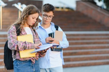 Okul çocukları açık havada kitap okuyor. Genç öğrenciler birlikte okuyor, derslere hazırlanıyor ve okulda bilgi paylaşıyorlar.