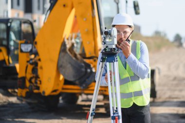 İnşaat alanında arazi inceleme aleti ve telsiz kullanan mühendis ya da arazi mühendisi.