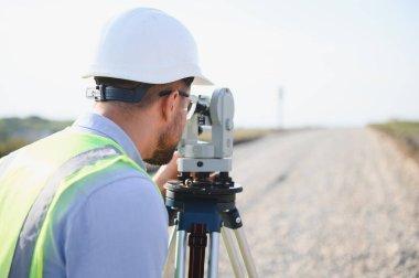 Yeni yol araştırması üzerinde çalışan profesyonel mühendis, doğru bir topoğrafya için ölçüm ekipmanlarını inceliyor.