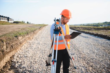 Yeni bir yol inşaatı alanında toplam bir istasyon kullanan mühendis, panodaki ölçümleri kontrol ediyor