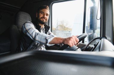 Kamyoncu olarak çalışan genç profesyonel bir adam, kameraya bakarken kendine güvenen bir kamyonet kullanıyor. Lojistiğe odaklanılıyor