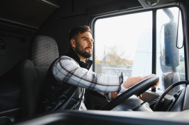 Ticari bir kamyon süren odaklanmış bir adam, yolda geziniyor, ulaşım, lojistik ve profesyonel sürüş mesleğini simgeliyor.