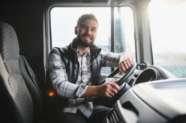 Sevkiyat teslimatı için kamyonet süren mutlu sakallı adam. Profesyonel işçi kulübede ellerini direksiyonda tutuyor.