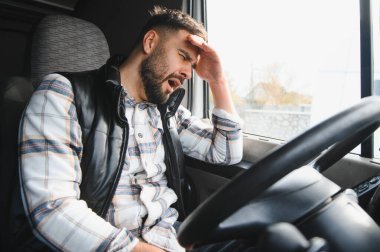 Kamyon kabininde otururken yorgun ve yorgun bir adam, yorgunluk ve yorgunluk yaşıyor.