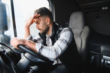 Stresli erkek kamyon şoförünün başı ağrıyor. Uzun bir yolculuktan sonra kabinde yorgunluk ve yorgunluk yaşıyor.