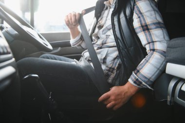 Kamyon kabininde emniyet kemeri takan sürücü, yol güvenliğini ve sorumlu ulaşımı öncelikli hale getiriyor.