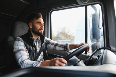 Kamyonet süren genç bir adam, direksiyon elinde, lojistik ve ulaşım sektöründe çalışıyor.