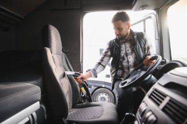 Profesyonel kamyon şoförü araç kulübelerinin koltuklarını ve zeminini süpürüyor, temiz ve düzenli bir çalışma ortamı sağlıyor.