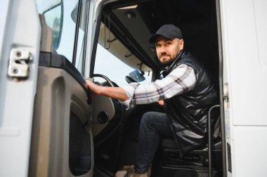 Kamyonetinin büyük kabininde oturan profesyonel erkek kamyon şoförü uzun bir yolculuğa hazır.