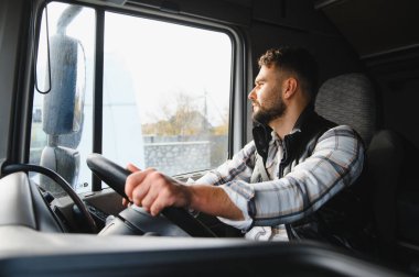 Önündeki yola odaklanmış ticari bir kamyon süren genç bir adam. Malların zamanında taşınması ve teslimatın sağlanması