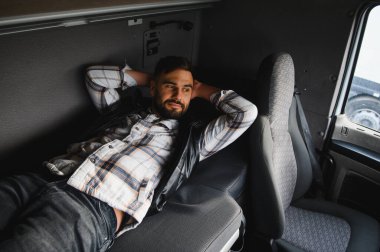 Kamyon kabinindeki ranzada dinlenen bir adam uzun mesafe ulaşım işine çok ihtiyaç duyuyor.