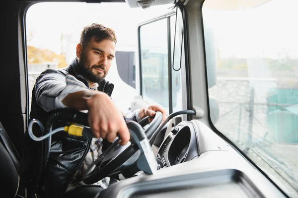 Kamyon süren bir adam, araç kabinine odaklanmış görünüyor. Ulaştırma sektöründe profesyonel çalışma