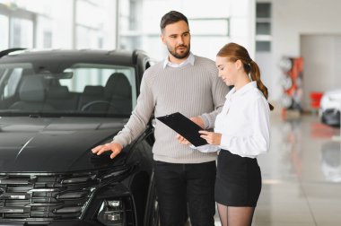 Satış görevlisi ve adam galeride yeni bir araba almayı tartışıyor. Otomobil satın alan yönetici asistanı istemci