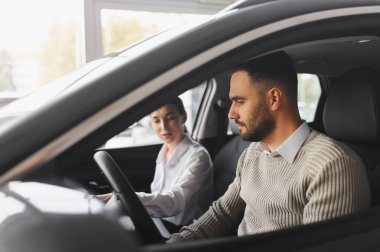 Otomobil galerisinde test sürüşü yapan adam, profesyonel satış elemanından denetim ve gösterge paneli öğreniyor.