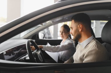 Erkek test sürüşü, yeni bir araba, satış elemanı ile etkileşim. Araç kabininin içindeki özellikleri açıklıyor.
