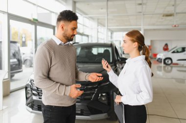 Araba satıcısı potansiyel bir müşteriyle konuşuyor. Parlak bir otomobil galerisinde yeni bir araç almak için.
