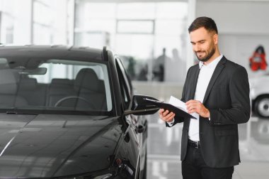 Modern bir bayilik ortamında araba satın almak için belge kontrolü ve evrak işleri yapan profesyonel bir araba satıcısı.