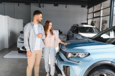 Genç bir çift farklı arabaları keşfediyor ve dokunuyor. Parlak bir bayide, satın alma kararı alıyorlar.