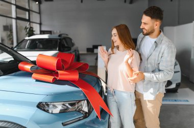 Mutlu adam yeni arabası ve kırmızı kurdelesi olan sürpriz bir kadın. Özel bir olayı kutlamak ve satın almak.