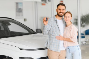 Çiftler yeni bir otomobil aldıktan sonra, gülümseyerek, kucaklaşarak ve araba anahtarlarını tutarak özgürlüklerini ve sahipliklerini kutluyorlar.