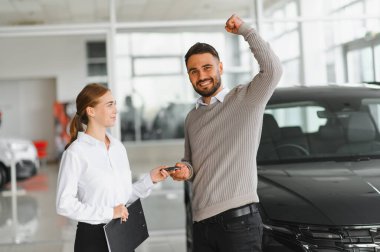 Müşteri, modern galerideki satış elemanlarından yeni araba anahtarlarının alınmasını kutluyor.