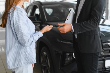 Satıcının müşteriye araba anahtarı vermesi, başarılı bir yeni araç alımını ve bir galeride mal mülkiyetini simgeliyor.