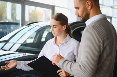 Galerideki bir adama araba özelliklerini açıklayan profesyonel bir satıcı. Araç alıp satmak