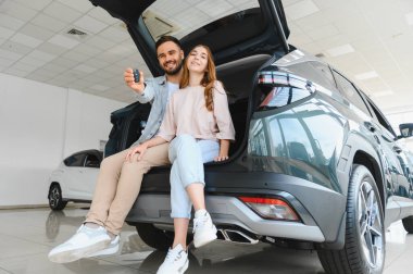 Yeni araba sahipliğini kutlayan mutlu çift, yakın zamanda satın aldıkları cipin bagajında oturuyorlar.