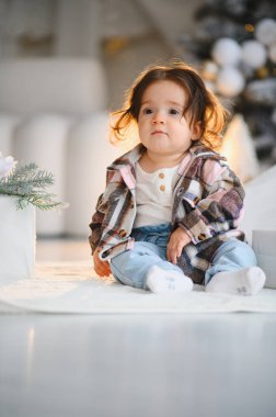 Yumuşak bir battaniyenin üzerinde oturan tatlı bebek, evde tatil kutlamaları ve kış kutlamalarını dört gözle bekliyor.