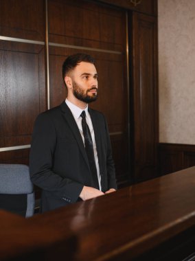 Koyu renk takım elbiseli profesyonel bir adam otel resepsiyonunda özenle duruyor. Lüks iş konukseverlik hizmeti sunuyor.