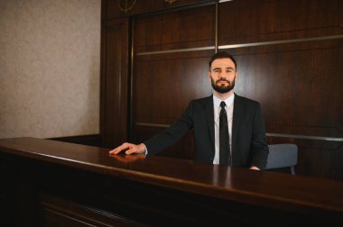 Erkek kapıcı ya da otel müdürü ahşap resepsiyon masasının arkasında profesyonel hizmet ve konukseverliği temsil ediyor.