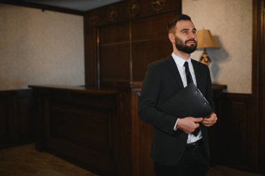 Otel resepsiyonunda elinde dosya tutan takım elbiseli bir adam. Konukseverlik ve iş hizmeti