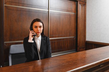 Kapıcı ya da yönetici olarak çalışan genç bir kadın otel lobisinde profesyonel müşteri hizmetleri sunuyor.